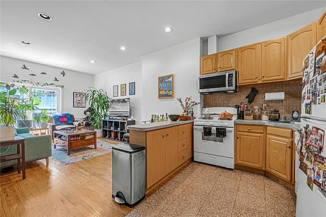 kitchen with kitchen peninsula, white appliances, light hardwood / wood-style flooring, and backsplash