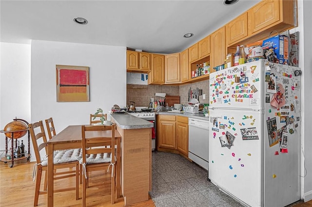 kitchen featuring light brown cabinets, wood-type flooring, white appliances, and backsplash