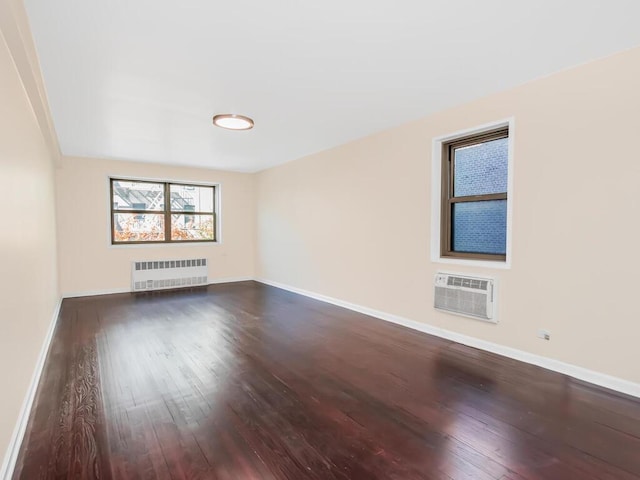 empty room with a wall mounted AC, radiator heating unit, and dark hardwood / wood-style floors