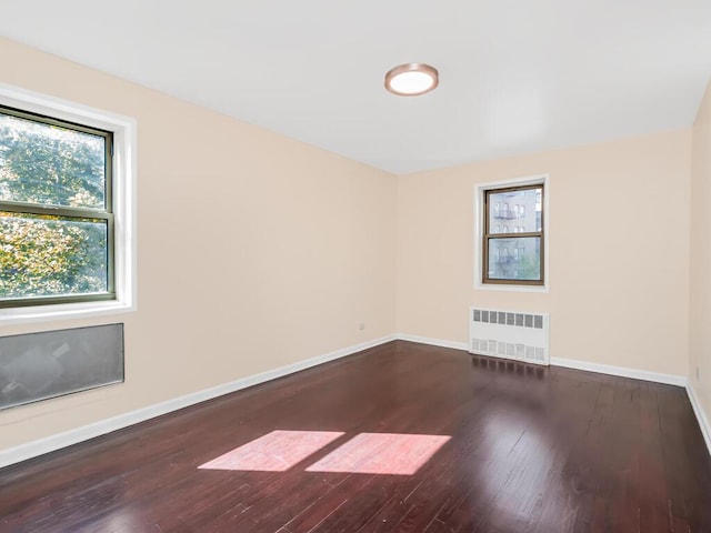 unfurnished room featuring radiator heating unit and dark hardwood / wood-style flooring