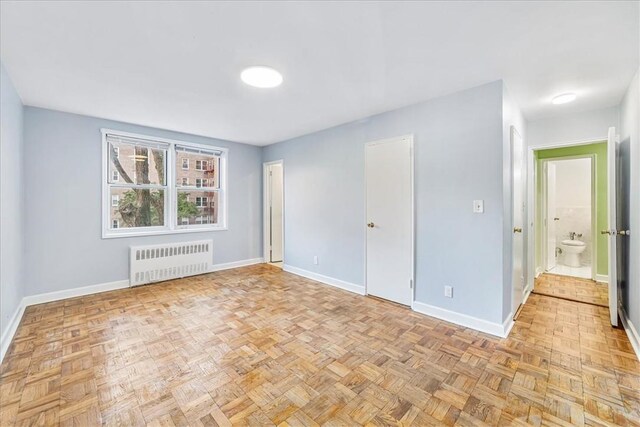 spare room with radiator heating unit and light parquet floors