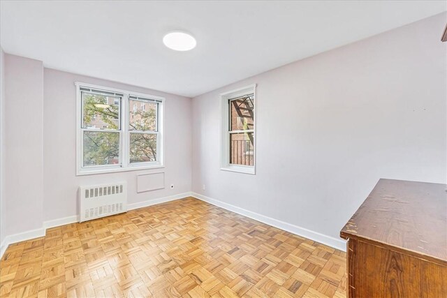 empty room featuring radiator heating unit and light parquet flooring