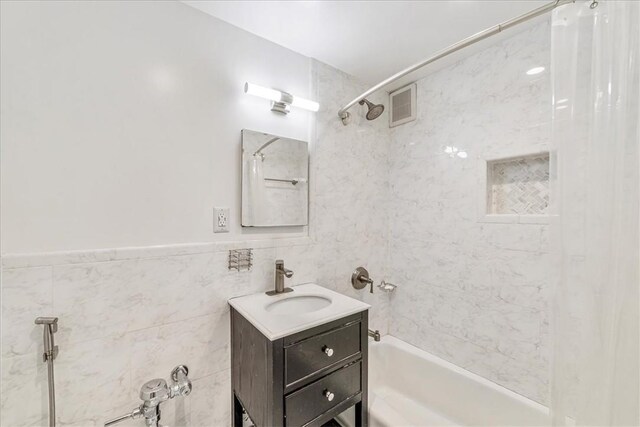 bathroom featuring tiled shower / bath combo, tile walls, and vanity