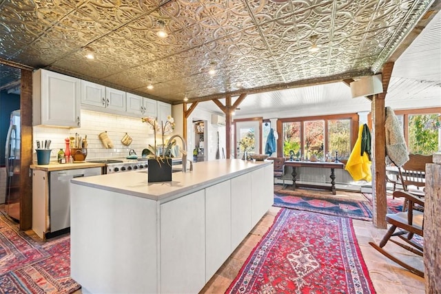 kitchen with sink, white cabinets, an AC wall unit, a kitchen island, and appliances with stainless steel finishes