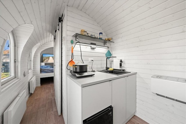 kitchen featuring sink, wood-type flooring, vaulted ceiling, wooden walls, and wood ceiling