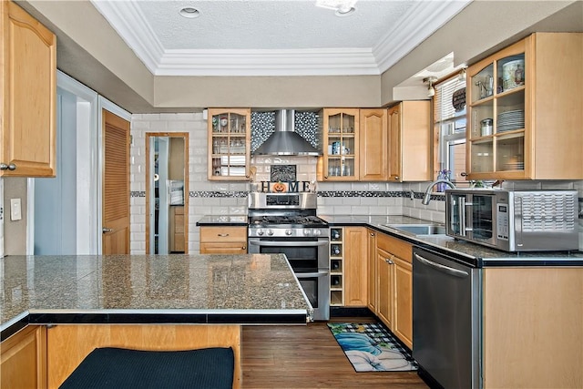 kitchen with wall chimney exhaust hood, a textured ceiling, stainless steel appliances, sink, and a breakfast bar area