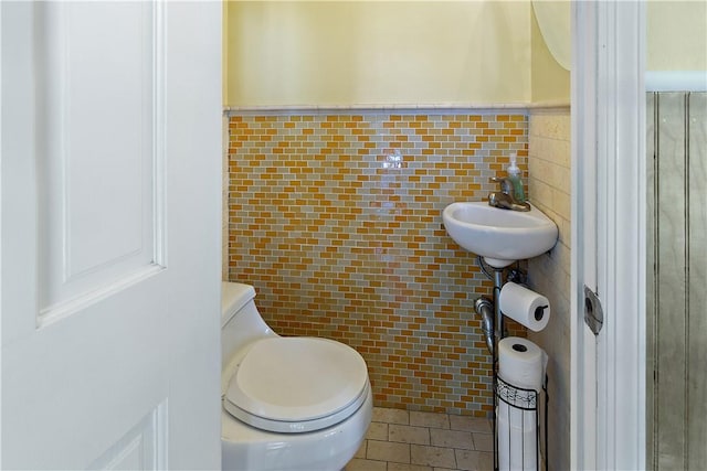 bathroom with sink, toilet, and tile walls