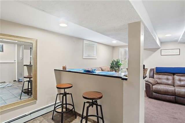 kitchen featuring a kitchen breakfast bar, light colored carpet, a textured ceiling, and a baseboard radiator