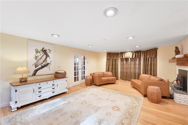 living area with a wood stove, light hardwood / wood-style flooring, and french doors