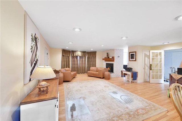 living room featuring a brick fireplace, french doors, and light hardwood / wood-style flooring