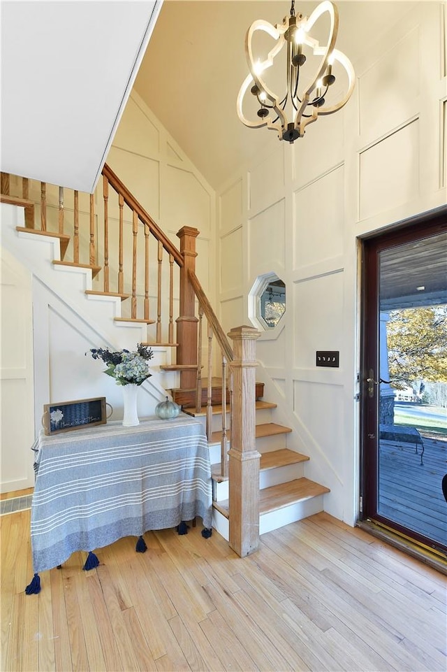 entryway featuring light hardwood / wood-style floors, vaulted ceiling, and a notable chandelier