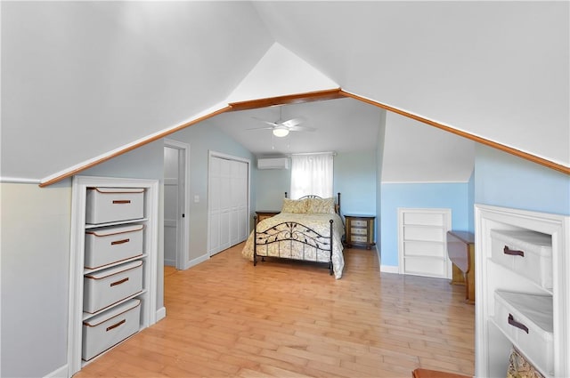 bedroom featuring light wood-type flooring, an AC wall unit, and lofted ceiling