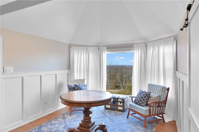 sitting room featuring a barn door, light hardwood / wood-style flooring, and lofted ceiling