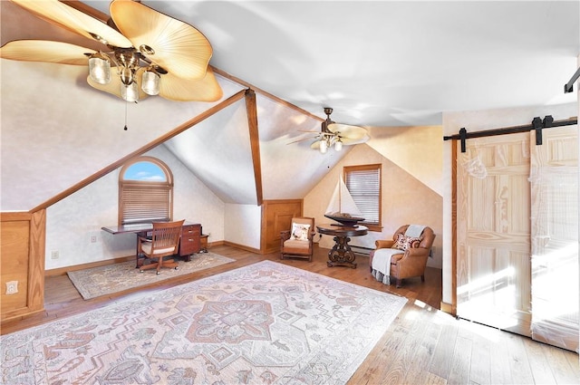 additional living space with hardwood / wood-style floors, ceiling fan, a barn door, and vaulted ceiling