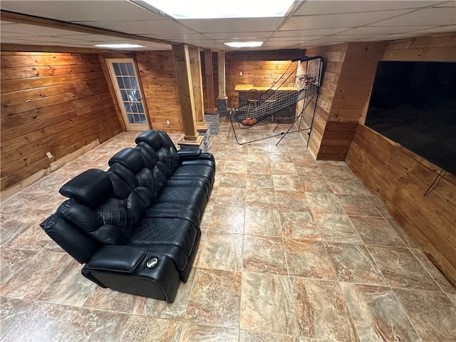 basement with a paneled ceiling and wood walls