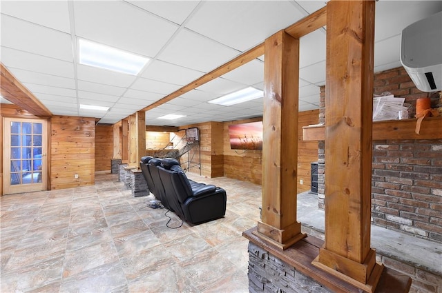 living room with a paneled ceiling and wooden walls