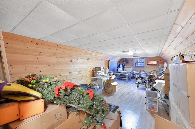 interior space featuring a paneled ceiling, lofted ceiling, hardwood / wood-style flooring, and wooden walls