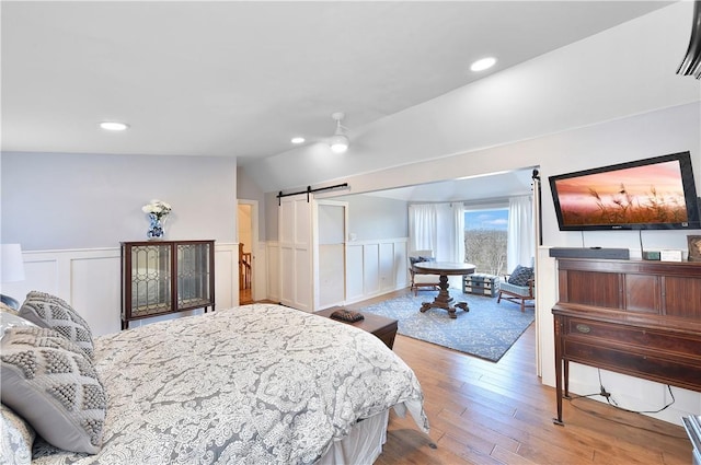 bedroom featuring lofted ceiling, hardwood / wood-style floors, and a barn door