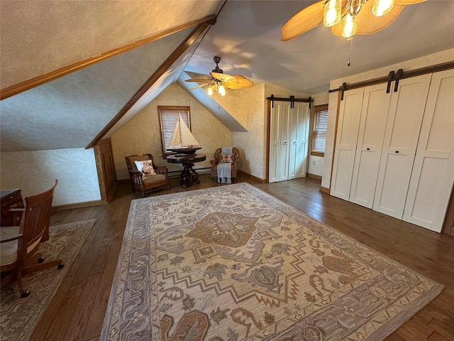 bonus room with a barn door, ceiling fan, lofted ceiling, and dark hardwood / wood-style flooring