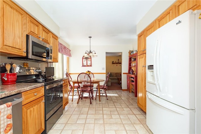 kitchen with appliances with stainless steel finishes, pendant lighting, and a notable chandelier