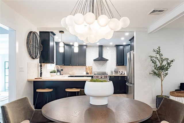 kitchen with wall chimney exhaust hood, a breakfast bar, tasteful backsplash, kitchen peninsula, and stainless steel appliances