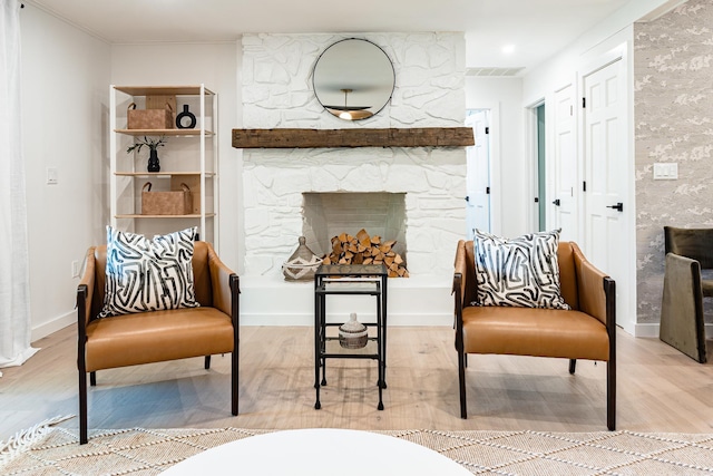 living area featuring a stone fireplace and light wood-type flooring