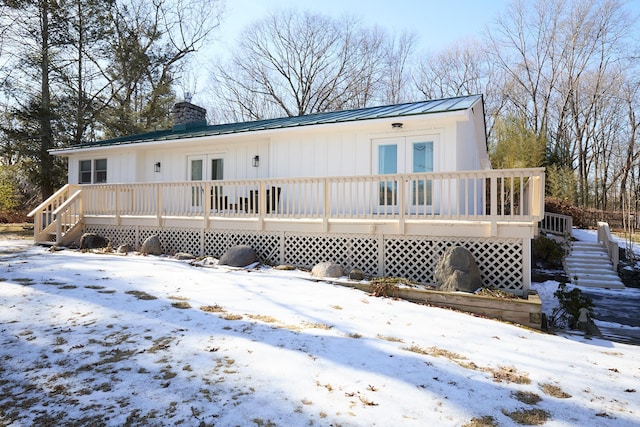 snow covered rear of property featuring a wooden deck and french doors