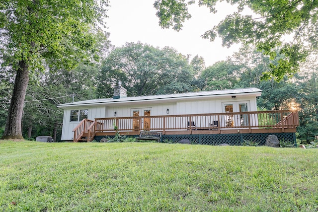 rear view of property featuring french doors, a yard, and a wooden deck