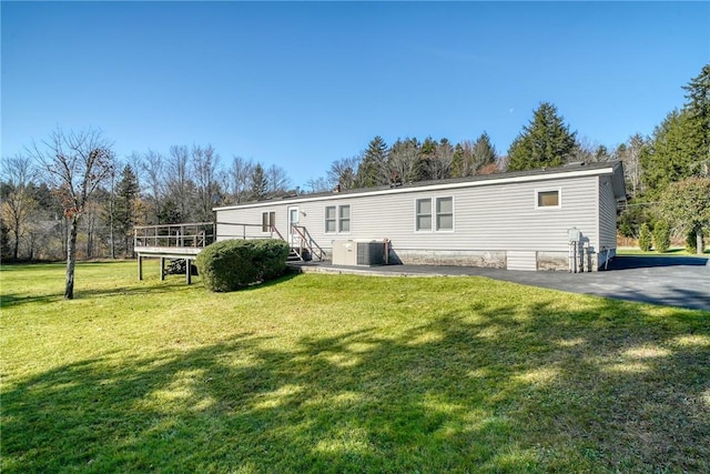 back of property featuring central AC unit, a yard, and a wooden deck