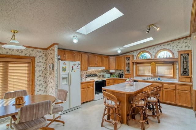 kitchen with a center island, lofted ceiling with skylight, a textured ceiling, white appliances, and a kitchen bar