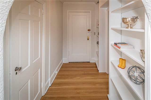 hallway with light wood-type flooring and ornamental molding