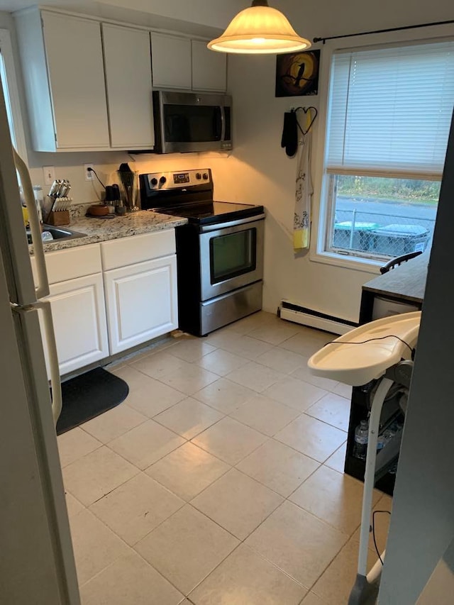 kitchen featuring white cabinets, hanging light fixtures, baseboard heating, light tile patterned flooring, and stainless steel appliances