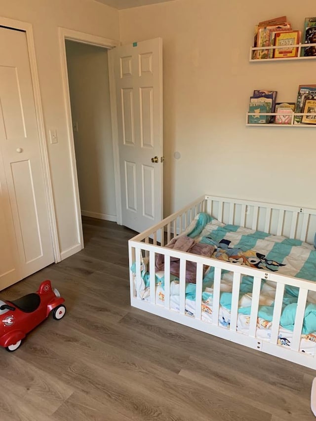 bedroom with hardwood / wood-style floors and a nursery area