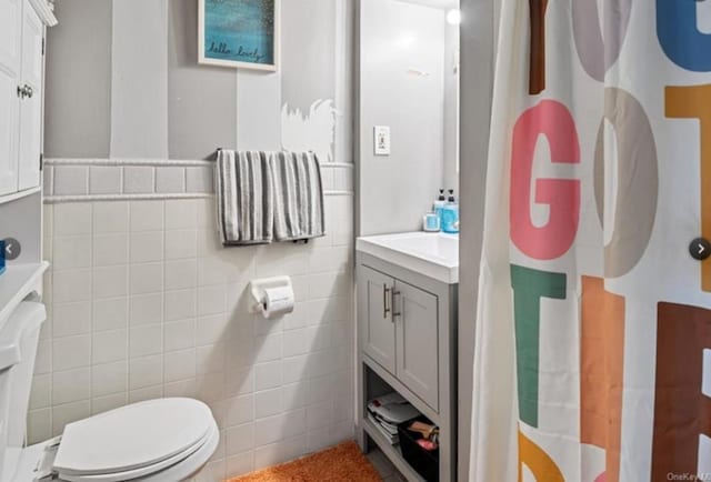 bathroom featuring vanity, toilet, and tile walls