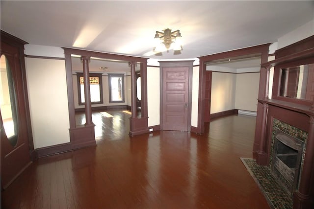 interior space featuring a baseboard radiator, ornate columns, and dark wood-type flooring