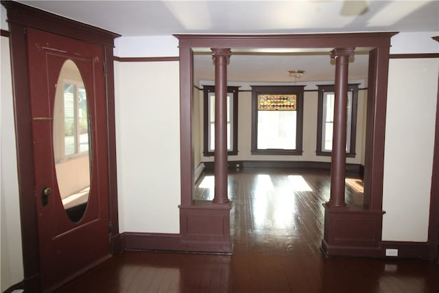 corridor with dark hardwood / wood-style flooring and ornate columns