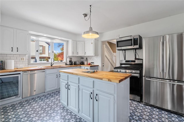 kitchen featuring white cabinets, decorative light fixtures, butcher block counters, and appliances with stainless steel finishes