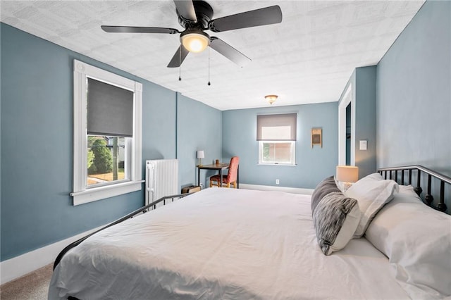 carpeted bedroom with ceiling fan, radiator, and multiple windows