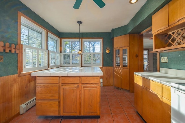 kitchen featuring ceiling fan, tile counters, a center island, a baseboard heating unit, and pendant lighting