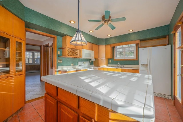 kitchen with light tile patterned floors, white appliances, tile countertops, and a wealth of natural light