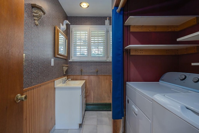 laundry area with washing machine and dryer, wooden walls, sink, and light tile patterned flooring