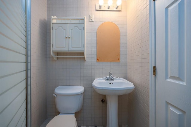 bathroom with sink, toilet, and tile walls