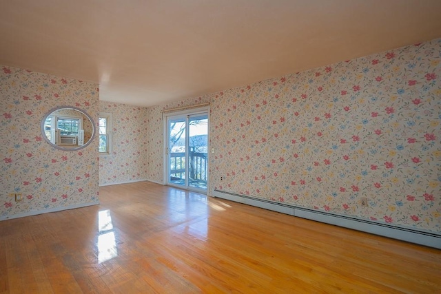 empty room with light hardwood / wood-style floors and a baseboard heating unit