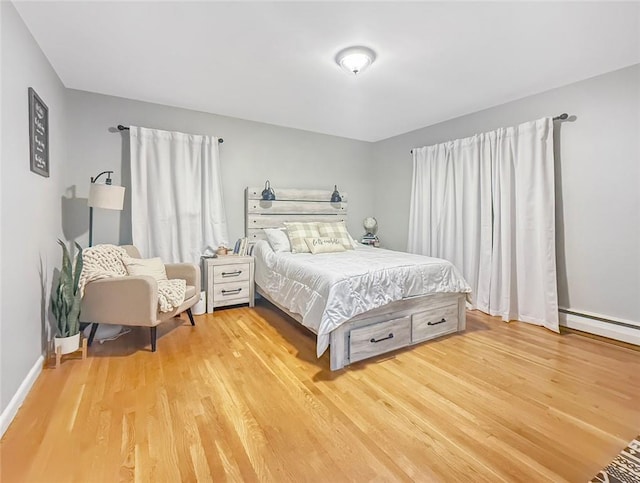 bedroom with light hardwood / wood-style flooring and a baseboard heating unit