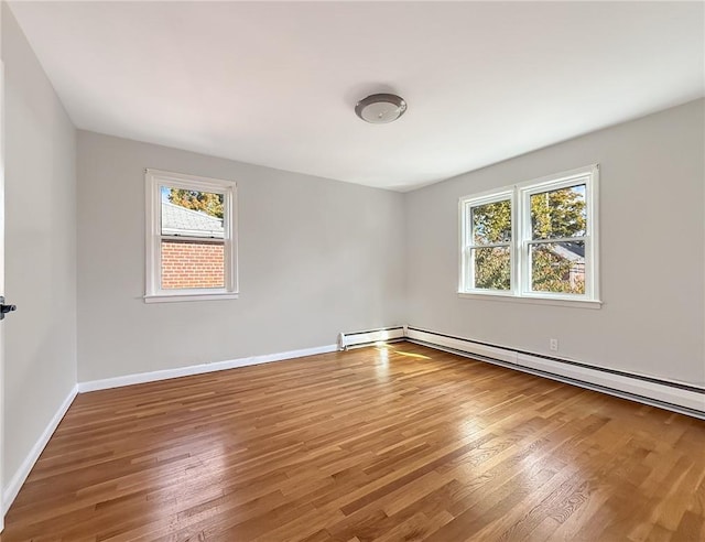 empty room featuring hardwood / wood-style floors and a baseboard heating unit