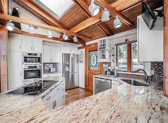 kitchen featuring light stone countertops, appliances with stainless steel finishes, white cabinetry, and sink