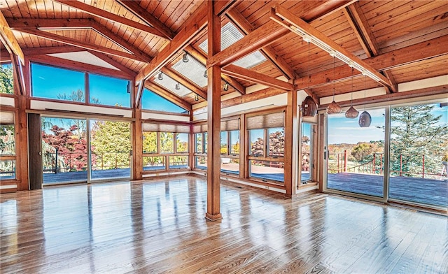 unfurnished sunroom featuring vaulted ceiling with beams, plenty of natural light, and wooden ceiling