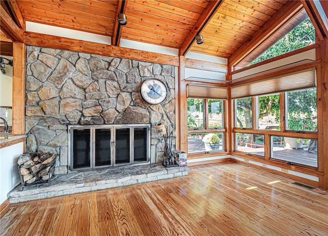 unfurnished living room with a stone fireplace, vaulted ceiling with beams, wooden ceiling, and hardwood / wood-style flooring