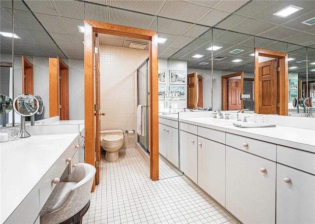 bathroom featuring a paneled ceiling, vanity, tile patterned flooring, toilet, and a shower with shower door