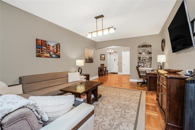 living room with built in shelves, light parquet floors, and a notable chandelier